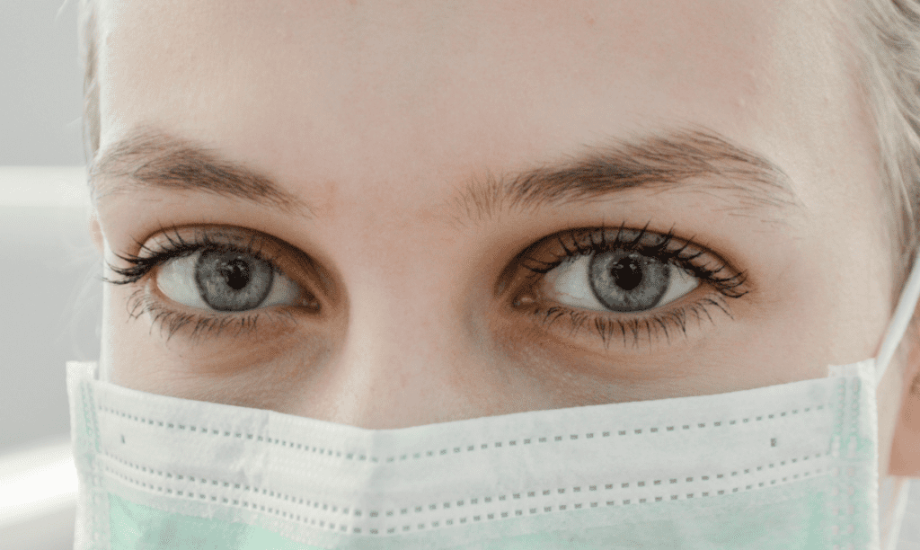 woman with fair complexion and green eyes wearing face mask